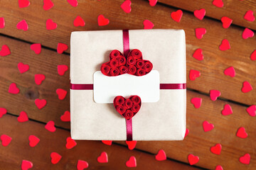 Gift box with empty tag and red ribbon and red hearts. Top view.