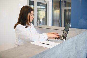friendly young woman behind the reception desk administrator