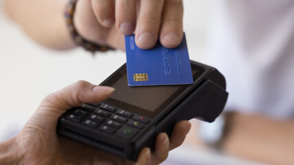 Male hand holding credit card at POS terminal device, using technology for electronic transaction,...
