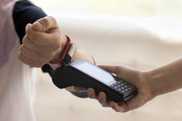 Customer paying bill for service, purchase, order in cafe, applying smartwatch to payment terminal...