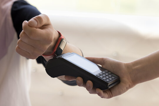 Customer paying bill for service, purchase, order in cafe, applying smartwatch to payment terminal for contactless electronic transaction, using online mobile bank service for smart gadget
