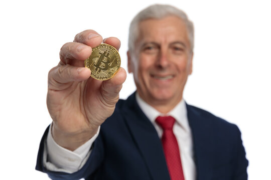 Old businessman presenting a bitcoin at the camera