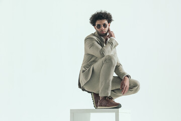 turkish man with curly hair wearing sunglasses crouching and posing