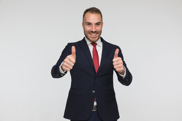 happy businessman in suit with red tie making thumbs up gesture and smiling