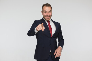 enthusiastic man in elegant suit smiling and pointing finger
