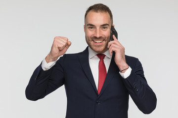 proud businessman in suit talking on the phone and celebrating victory