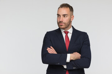 confident businessman in elegant suit looking to side while crossing arms
