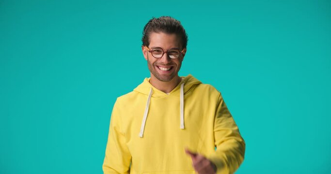 casual Arabic man with curly hair smiling and making thumbs up gesture with hands while laughing and being happy on blue background