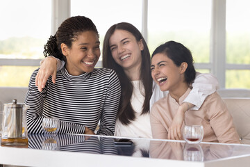 Diverse group of cheerful excited pretty girls enjoying meeting in cafe, talking, laughing,...