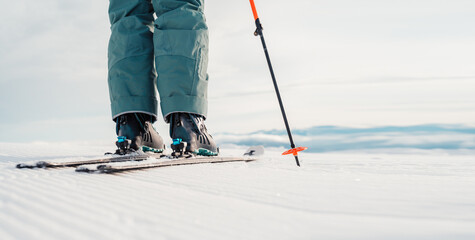 Woman in skiing clothes with helmet and ski googles on her head with ski sticks. Winter weather on...