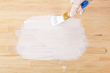 white paint with a brush painting a wooden background with texture