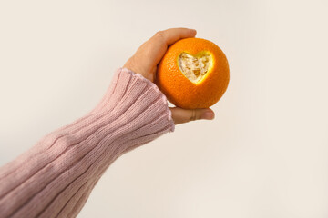 female hand holds, offers orange, beautiful composition with heart carved in citrus, concept of love, vitamins, healthy eating, healthy life, idea for design for Valentine's Day, Mother's Day, wedding