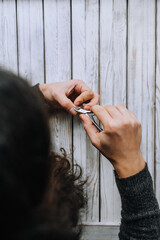 Hands of a woman, a girl close-up, making herself a manicure, cutting cuticles with scissors on fingers, nails on a wooden background. Close-up photography, work, beauty, art.