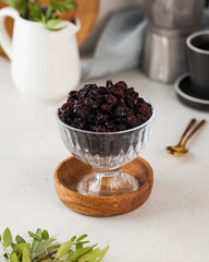 Fototapeta na wymiar Dried brown raisins in bowl on a wooden stick. Healthy snack. 