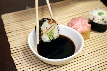 Two chopsticks take sushi. Sushi rolls and soy sauce
