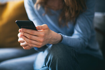Young woman using a mobile phone on the couch at home - 561638628