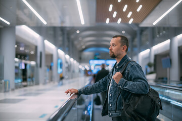 A man with a backpack moves to the gate on a travelator at the airport.