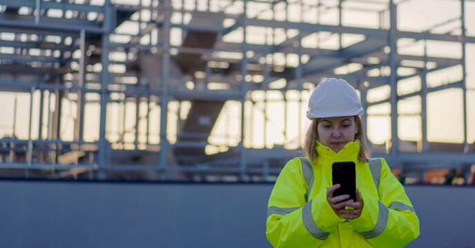 Construction woman on site using mobile - Hard hat engineer visiting construction site - Female construction worker managing team - Woman using mobile on construction building site - woman on site