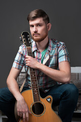 A guy holds a guitar in his hands, thinking about a new composition