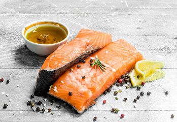 Raw salmon fish steaks with spices and lemon wedges.