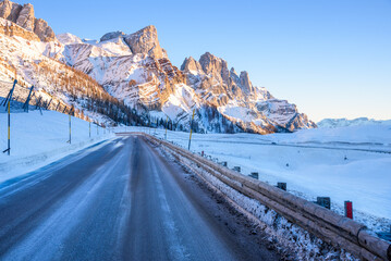 Deserted icy mountain pass road in the Alps at sunset