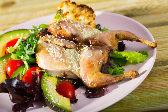 Quail-tobacco with sesame and salad of avocado is tasty dish in the kitchen.