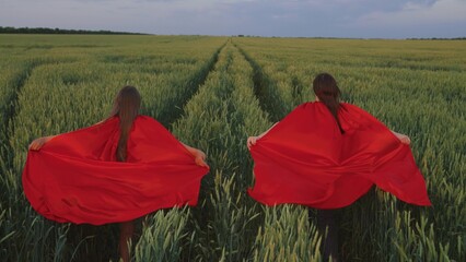 Children's games, dreams teenagers, of becoming superhero. Young girls in red cloak. Happy...