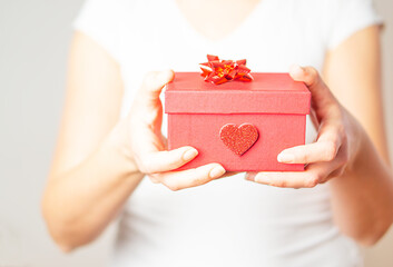 Close up shot of the female hands holding a small gift in a red box. Valentine gift.