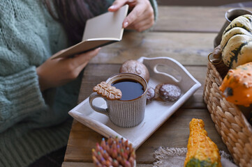 Coffee and book in autumn. Woman reading a book and drinking coffee with cookies. Atmosphere of comfort and tranquility. High quality photo