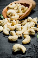 Cashew nuts in a wooden scoop with leaves.
