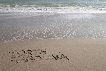Fototapeta premium North Carolina written in the sand at the beach