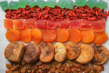 Different tasty dried fruits on paper, flat lay