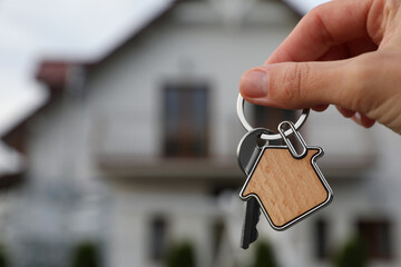 Woman holding house keys outdoors, closeup with space for text. Real estate agent