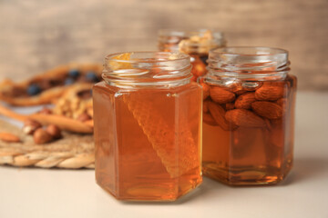 Jars with nuts and honey on beige table