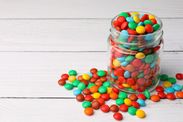 Tasty colorful candies on white wooden table, space for text