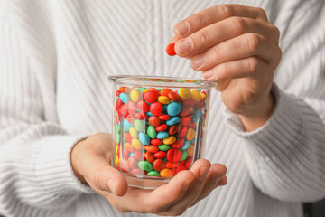 Woman with glass of tasty colorful candies, closeup