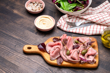 Roast beef sliced with capers and spinach leaves. keto diet food