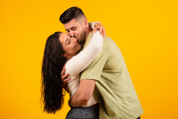 Satisfied handsome millennial middle eastern man hugging and kissing female, couple enjoy free time