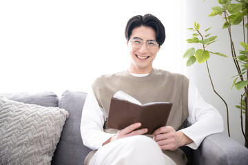 リビング(部屋)で本を読む男性　カメラ目線