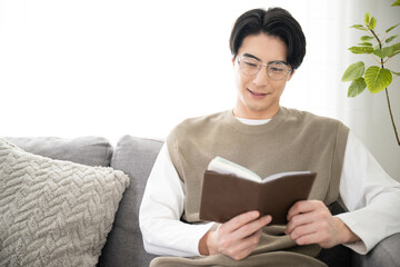 Asian man reading a book in the living room (room)　 - obrazy, fototapety, plakaty