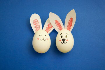 Food photo for Easter. Chicken eggs with cute cartoon rabbit face and bunny ears on blue background. Easter coloring book for kids. Greeting card for holiday Happy Easter. Congratulation. Copyspace