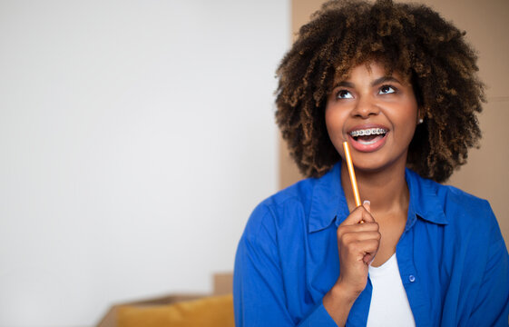 Black Woman With Pencil In Hand Dreaming About Interior Of New Flat