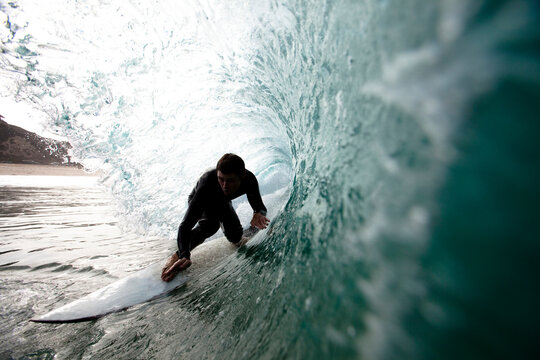 A male surfer navigates the barrel while surfing at Westward in Malibu, California.