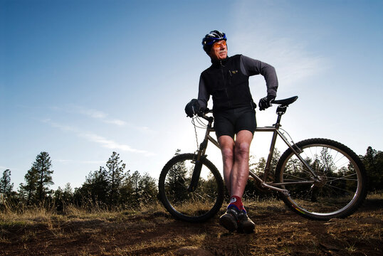A senior man poses for a portrait on his mountain bike in Flagstaff, Arizona.