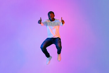 Fototapeta na wymiar Emotional african american man showing thumb ups on colorful background