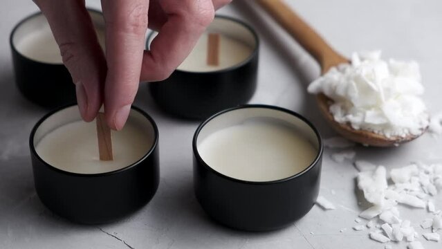 Woman's hand puts a wick in a soy wax candle