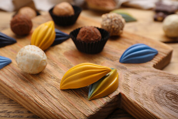 Different tasty chocolate candies on wooden board, closeup