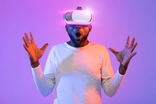 Shocked african american guy with VR headset gesturing