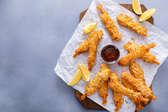 Tempura shrimp on a board served with sweet and sour sauce