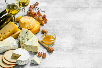 Assortment of types of cheese with white wine and honey.
